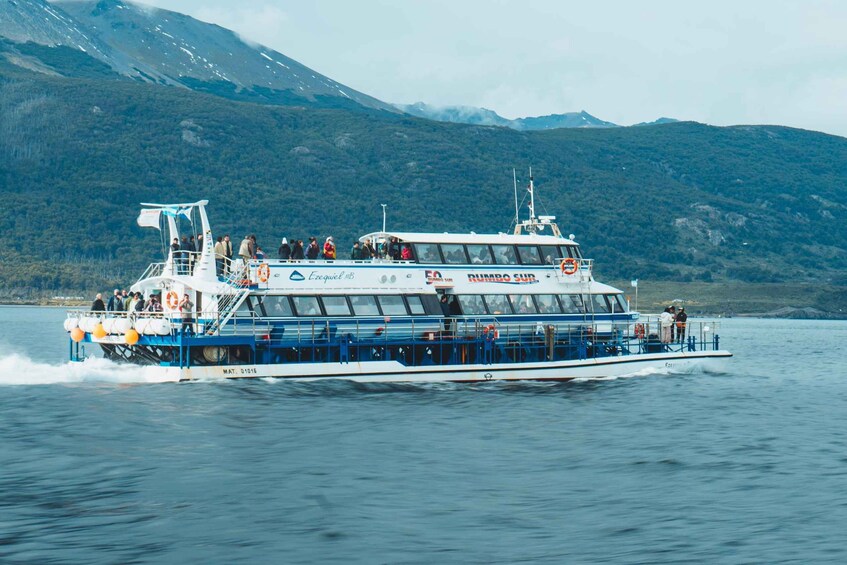 A ferry with passengers, moving on a body of water with mountains in the background. 2