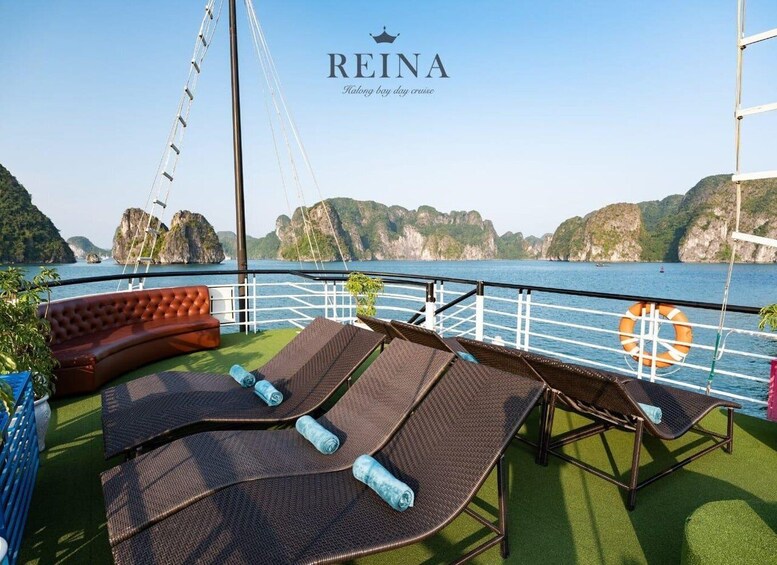 A deck with lounge chairs and a sofa overlooking a body of water with cliffs. 4