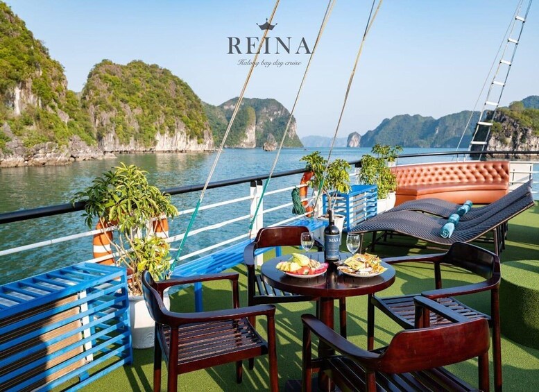A boat deck with outdoor seating, a table with food and drinks, and a view of the water and hills. 3