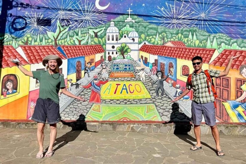 A mural with a central pyramid labeled 'ATACO', surrounded by colorful buildings and a church. 2
