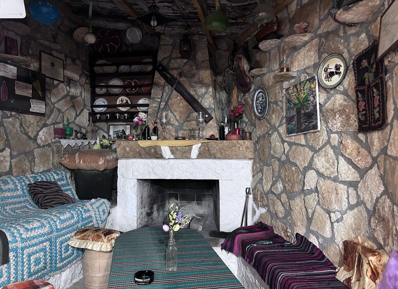 A cozy living room with a stone wall, a fireplace, a patterned sofa, and a colorful rug. 3