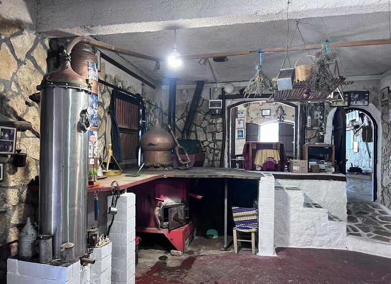 A rustic kitchen with stone walls, a large copper still, and a traditional oven. 4