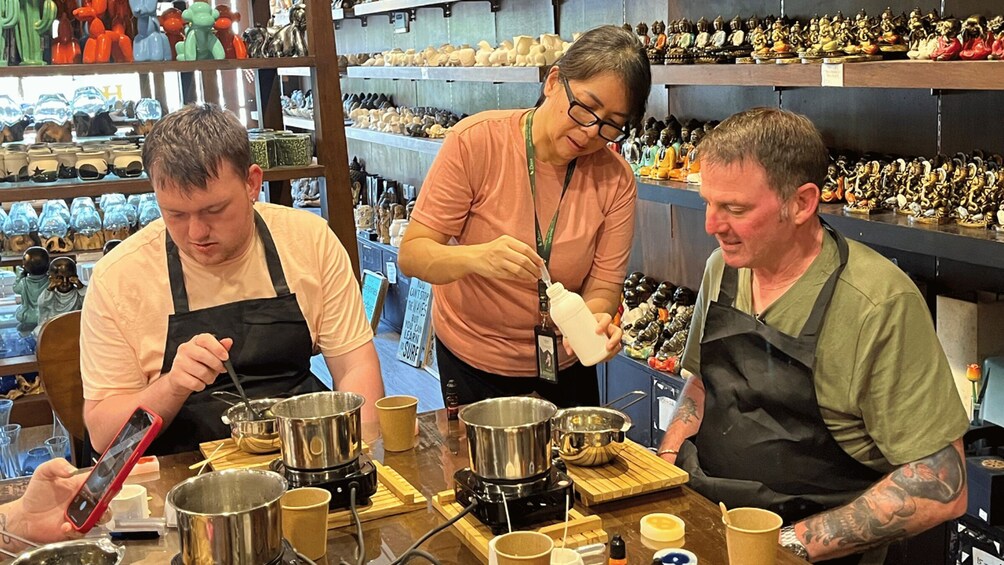 Three people cooking in a kitchen with pots and pans on the counter. 2