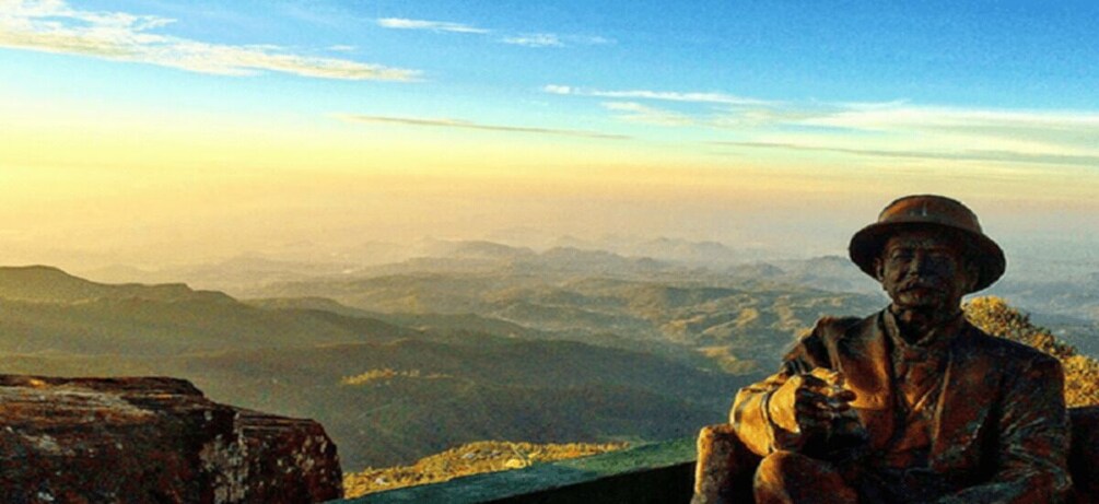 A statue of a man in a hat overlooking a mountainous landscape. 2