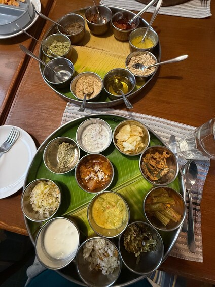 A variety of dishes served on banana leaves and metal plates. 5