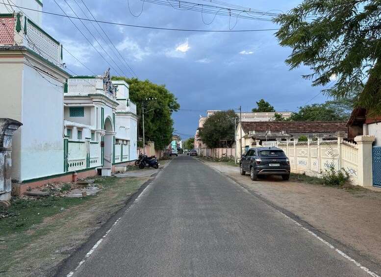 A quiet street lined with traditional houses, a parked car, and a motorcycle. 2