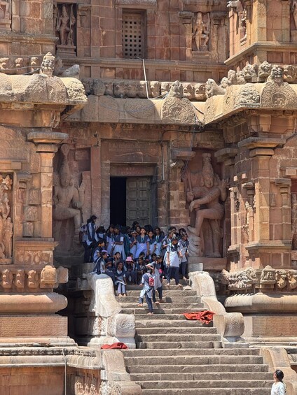 A group of people at the entrance of a temple with intricate carvings and statues. 4