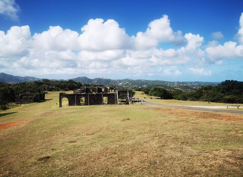 A historical site with ruins, a grassy field, and mountains in the background. 3