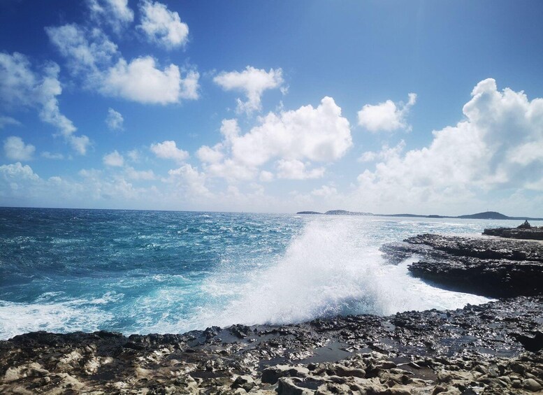 A rocky coastline with waves crashing against the rocks under a clear blue sky. 4