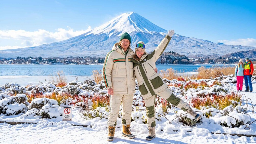 Two people posing in a snowy landscape with a mountain in the background. 2