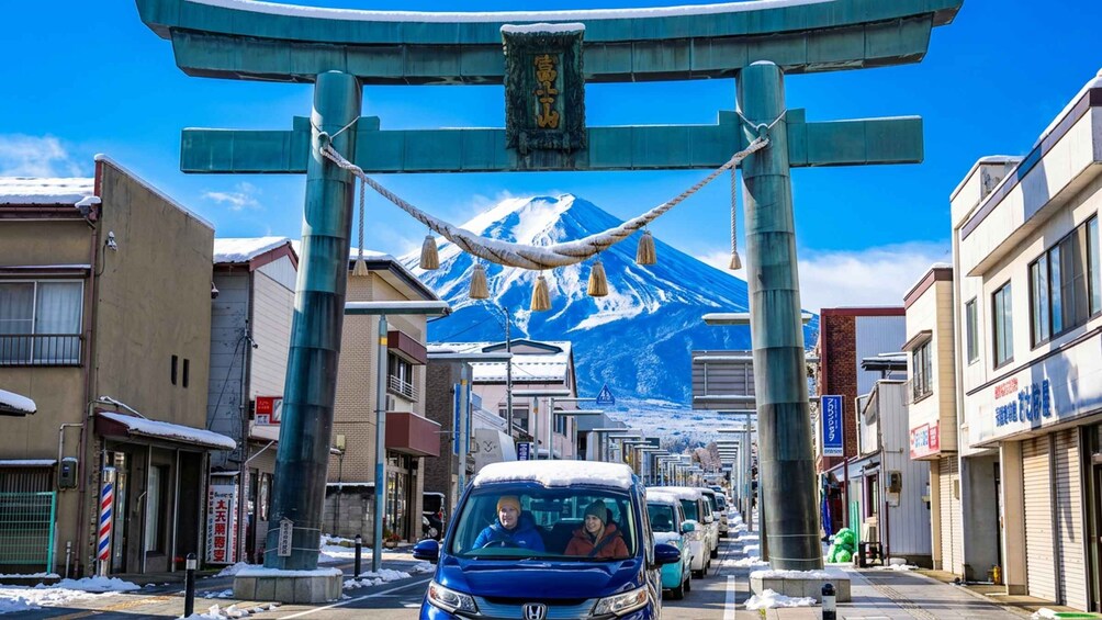 A street with a blue car, buildings, and a large mountain in the background. 3