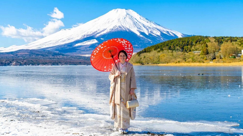 A person standing on a frozen lake with a snow-capped mountain in the background. 2