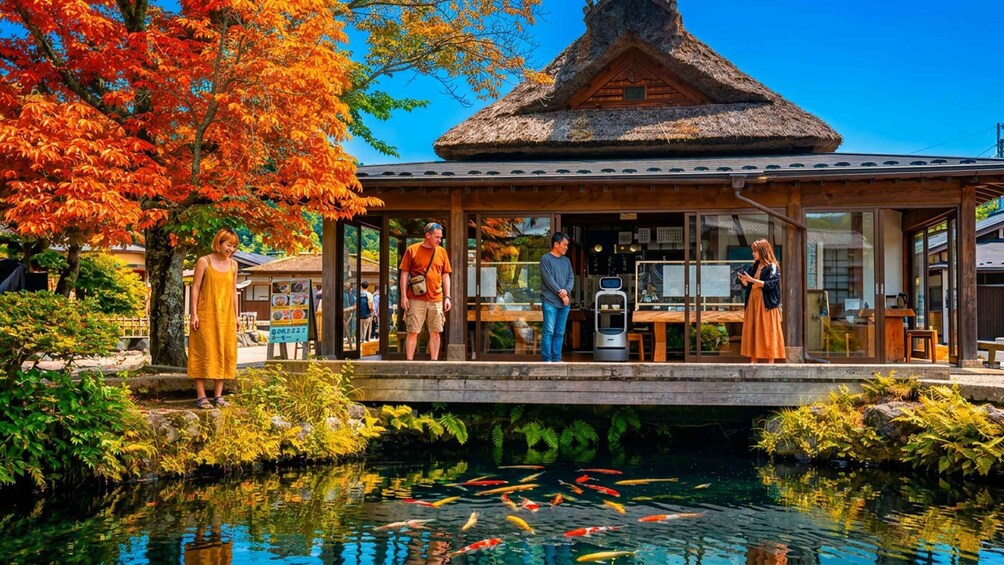 A traditional Japanese building with a thatched roof, a koi pond with colorful fish, and autumn foliage. 3