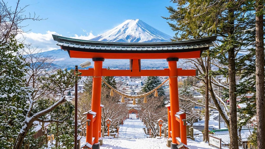 A snow-covered shrine with a red torii gate, a rope bridge, and Mount Fuji in the background. 4