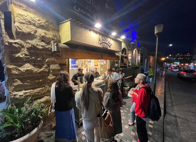A group of people standing outside a restaurant with a stone facade and a sign that reads "AQUAFINA." 3