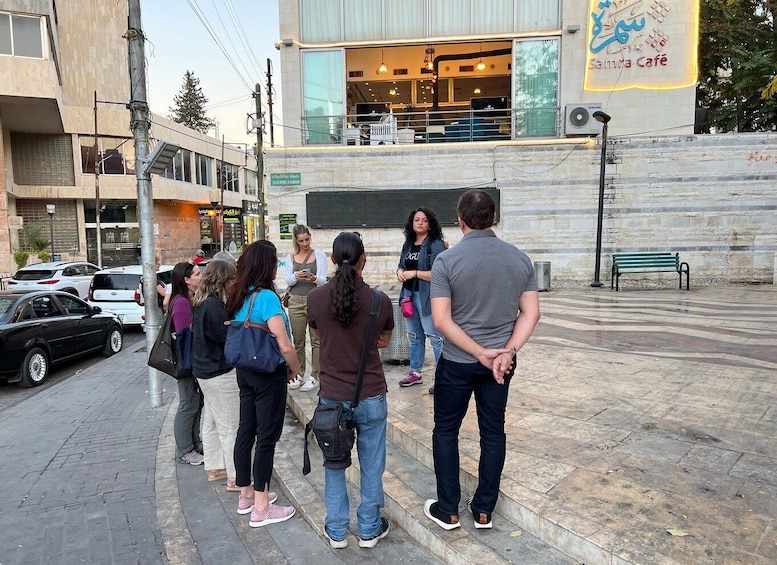 A group of people standing on a sidewalk in front of a building with a sign that reads "Samira Café". 4
