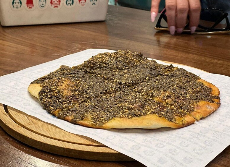 A flatbread topped with za'atar on a wooden board. 5