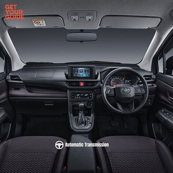 The interior of a car with a steering wheel, dashboard, and gear shift. 2