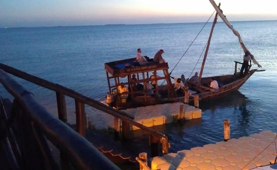 A wooden boat with people on it, docked at a pier. 3
