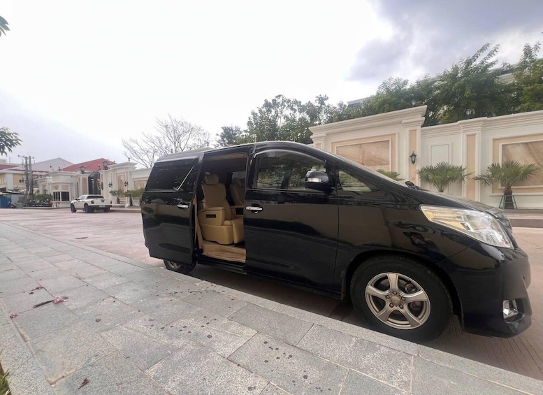 A black minivan parked on a paved area with a building in the background. 1