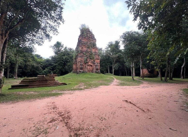 A temple complex with a central tower, surrounded by trees and a dirt path. 5
