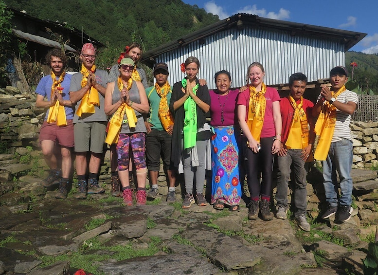 A group of people standing on a rocky path with a corrugated metal building in the background. 5