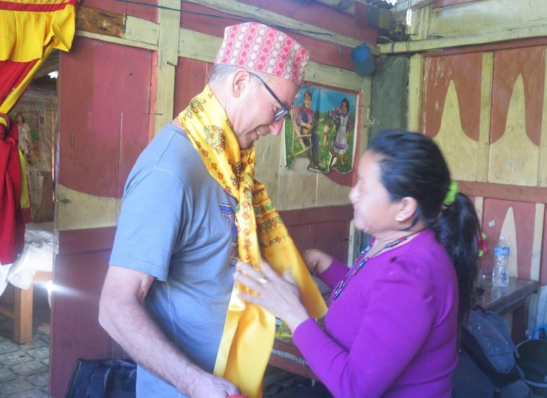 A man wearing a patterned cap and a yellow scarf, interacting with a woman in a purple sweater. 4