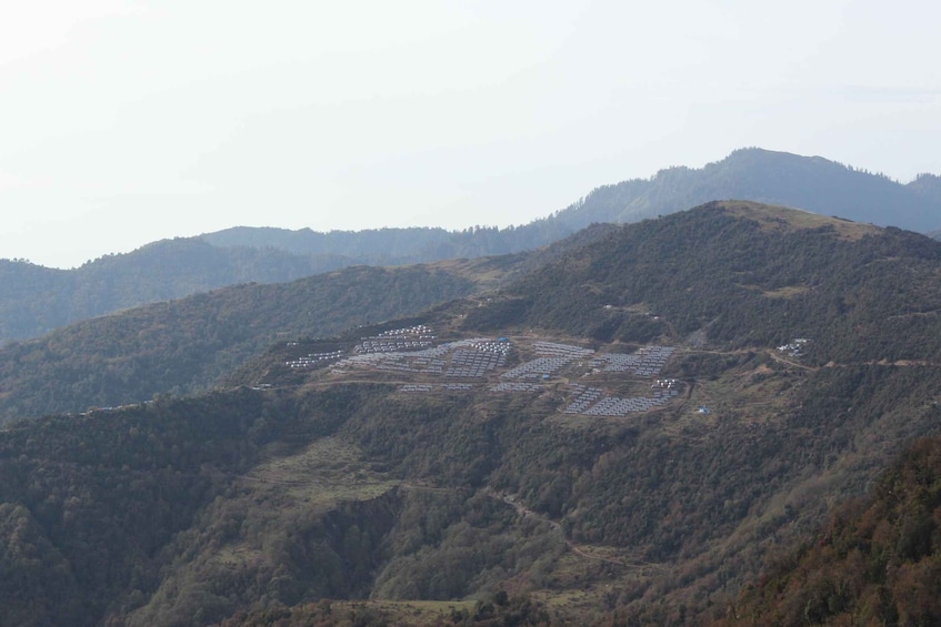 A mountainous landscape with a grid of solar panels on a hillside. 3
