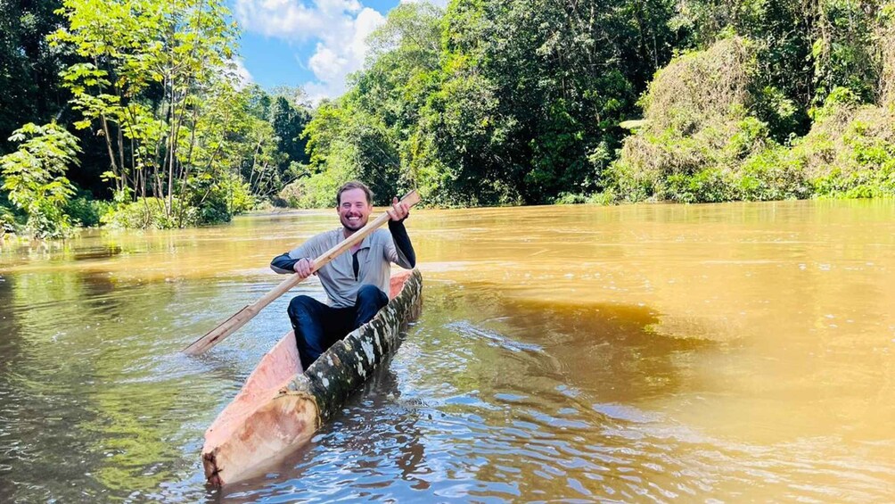 A person rowing a canoe on a river surrounded by dense greenery. 2