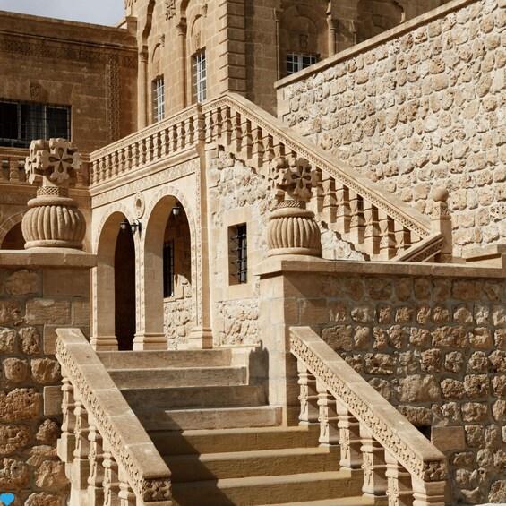 A stone staircase with ornate balustrades leading up to a building with arches and columns. 4