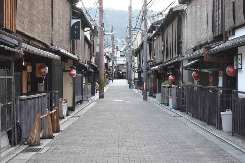 A narrow street lined with traditional buildings, red lanterns, and wooden fences. 4