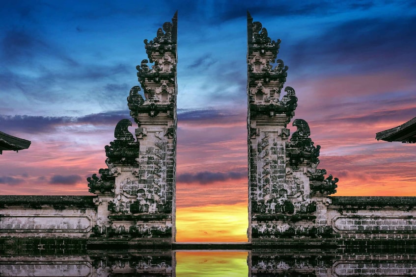 A symmetrical temple entrance with intricate carvings, set against a vibrant sunset sky. 1