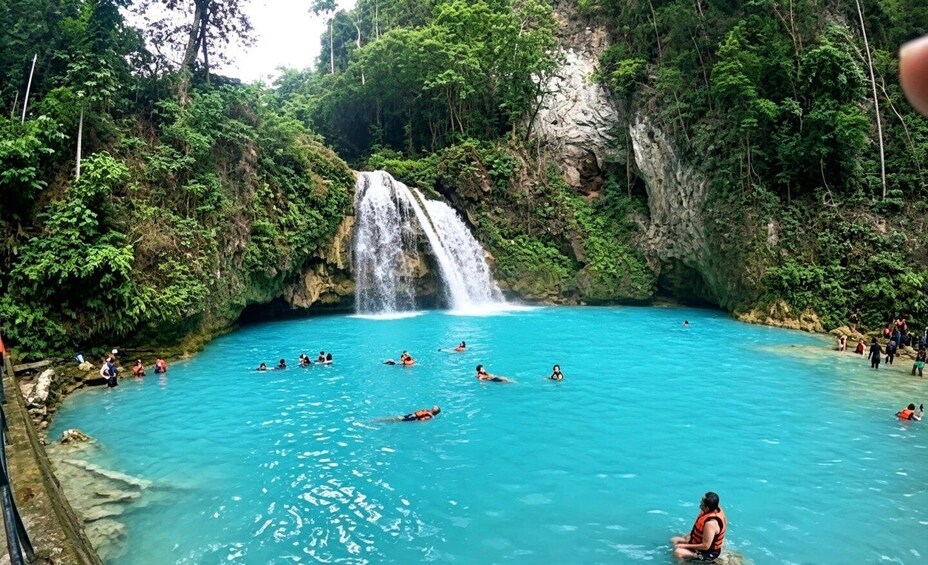 A waterfall cascading into a turquoise pool surrounded by lush greenery. 1