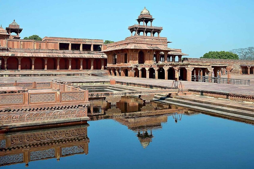 A historic building with intricate architecture, a reflection pool, and a clear blue sky. 4