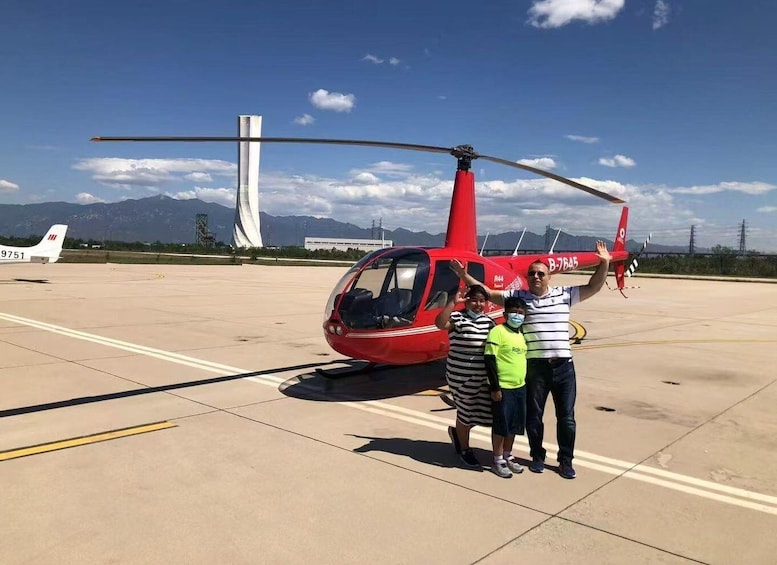 A red helicopter with the registration B-7645 on a tarmac, with mountains in the background. 1