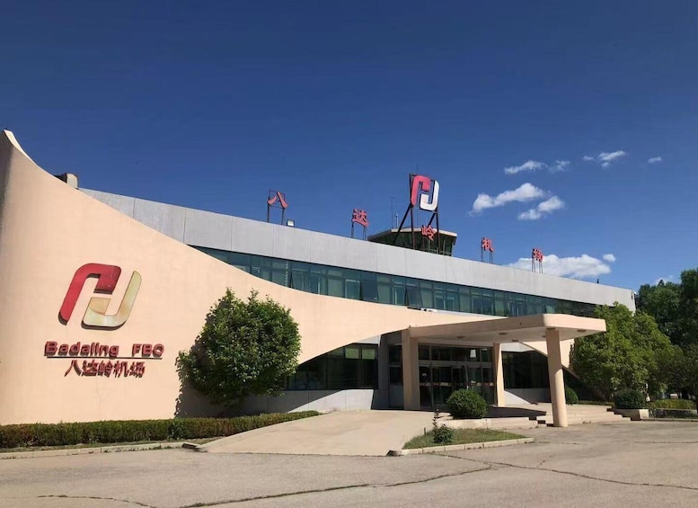 A modern building with a curved facade, a large entrance, and flags on the roof. 5