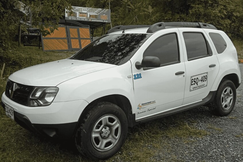 A white SUV parked on a gravel path with a sign in the background. 2