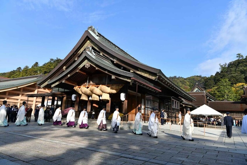 A traditional Japanese building with a curved roof and wooden beams. People in traditional attire are walking in front. 1