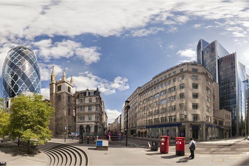 A city square with historic buildings, a modern glass structure, and a red telephone booth. 1