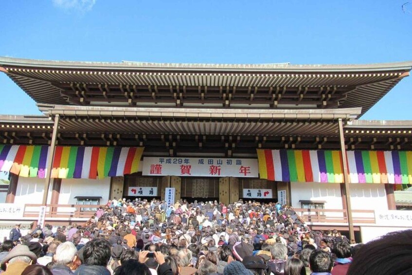 A traditional Japanese building with a large crowd gathered in front. 1