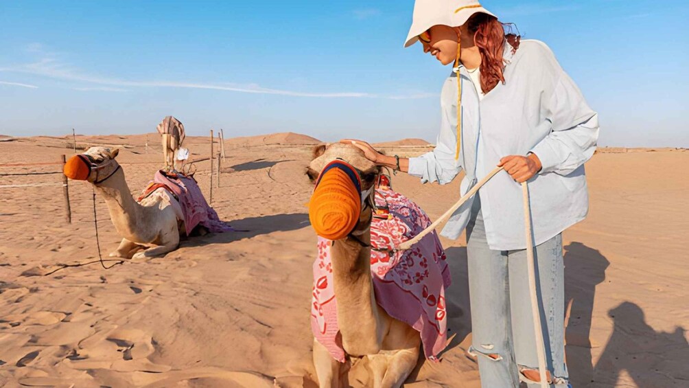 A person leading a camel in a desert with another camel in the background. 4