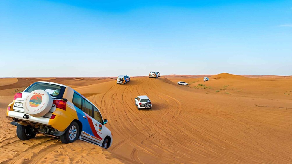 A convoy of off-road vehicles navigating a desert landscape with sand dunes. 3