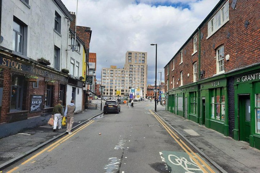 Una strada con negozi, una pista ciclabile e un edificio alto sullo sfondo. 5