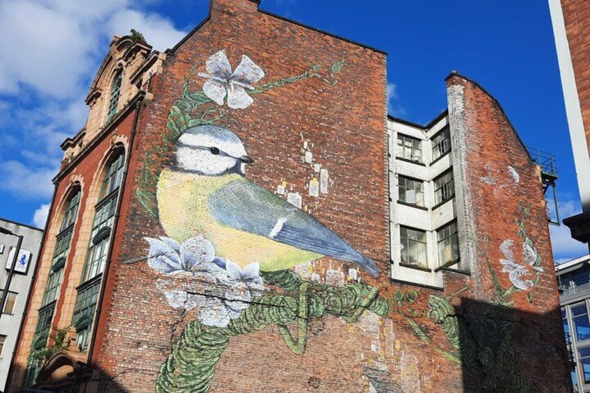 Ein Gebäude mit Wandgemälde von einem Vogel und Blumen. 2