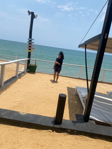 A beach with a signpost, a person, and a beach umbrella. 2