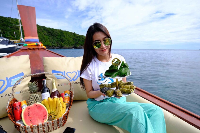A person on a boat holding a plate of food and a basket with drinks and fruits. 4