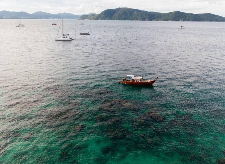 A boat on a calm sea with clear water and distant mountains. 1