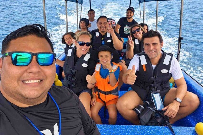 Un grupo de personas en un bote usando chalecos salvavidas, con una persona levantando el pulgar. 3