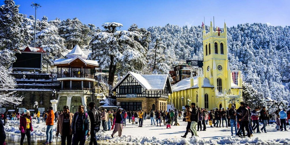 A snowy town square with a church, a clock tower, and traditional buildings. 1