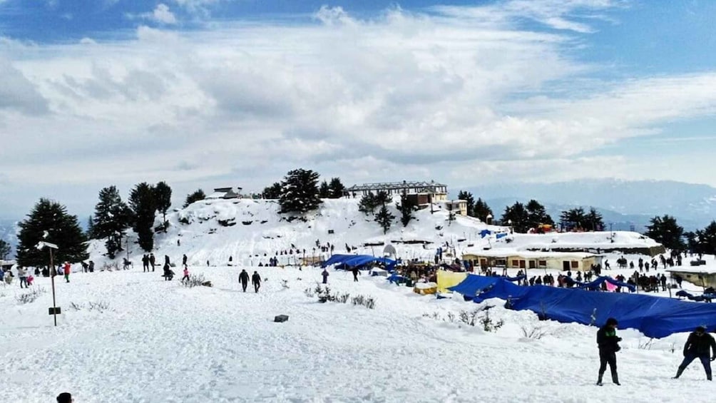 A snowy ski slope with people skiing and a building on a hill in the background. 3